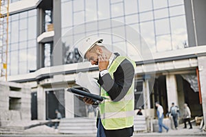 European engineer in helmet looking at paper plan