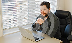 European enterpreneur working with laptop at office, sitting at desk.