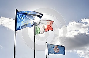 European flag, italian flag and Nemi`s flag waving together in a clear sky. Relationship between the European Union and the Italy