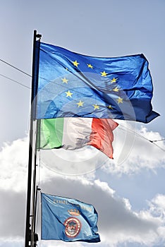 European flag, italian flag and Nemi s flag waving together in a clear sky. Relationship between the European Union and the Italy