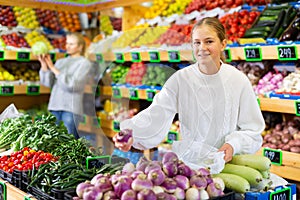 European girl purchaser choosing oranges in a grocery store