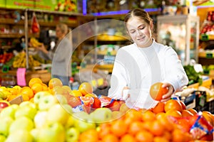 European girl purchaser choosing oranges in a grocery store