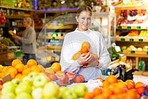 European girl purchaser choosing oranges in a grocery store