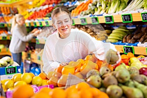 European girl purchaser choosing oranges in a grocery store