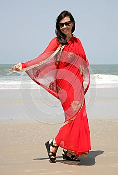 European girl in a red sari on the seashore on the Varka beach in Goa India