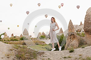 European girl standing with hot air balloons and rocks on background in Capadocia.