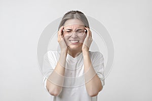 European girl in white t-shirt suffers from terrible headaches and compresses the head with fingers.