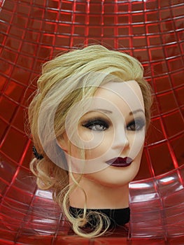 European hairstyle on the head of a mannequin on a red background. Close up