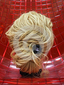 European hairstyle on the head of a mannequin on a red background.