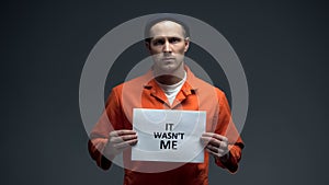European imprisoned man holding It was not me sign, wrongly convicted person