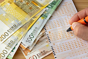 European lotteries, Lottery ticket, Stack of Euro banknotes, Hand with pen, Crossing out lucky numbers, Winning the draw