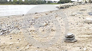 European male hand building stone stack at a river shore in tranquil atmosphere with calm movement of fingers and pebbles shows ze