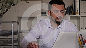 European male office worker sitting at desk and doing paperwork.