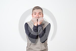 European man covering his mouth with both hands, looking shocked.