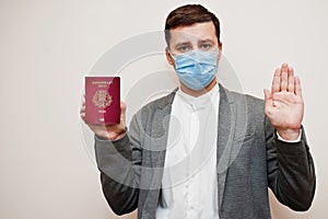 European man in formal wear and face mask, show Estonia passport with stop sign hand. Coronavirus lockdown in Europe country