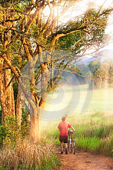 European man walking with bicycle in a forest