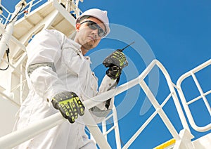 European man in white workwear and helmet with VHF photo
