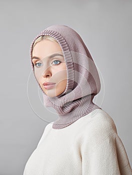 European Muslim woman with a blonde hair in a bonnet hood dressed on her head. Beautiful girl in sweater with soft skin, natural