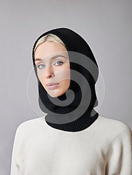 European Muslim woman with a blonde hair in a bonnet hood dressed on her head. Beautiful girl in sweater with soft skin, natural