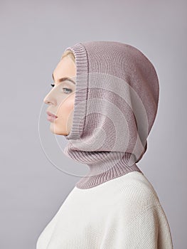 European Muslim woman with a blonde hair in a bonnet hood dressed on her head. Beautiful girl in sweater with soft skin, natural