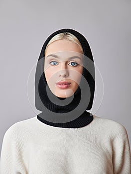 European Muslim woman with a blonde hair in a bonnet hood dressed on her head. Beautiful girl in sweater with soft skin, natural