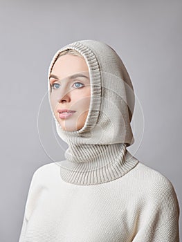 European Muslim woman with a blonde hair in a bonnet hood dressed on her head. Beautiful girl in sweater with soft skin, natural