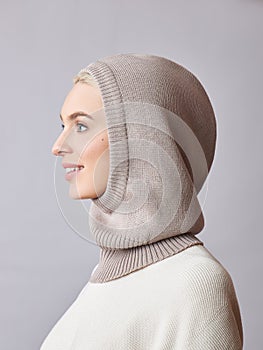 European Muslim woman with a blonde hair in a bonnet hood dressed on her head. Beautiful girl in sweater with soft skin, natural