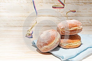 European New Year and carnival doughnuts, called Berliner or Krapfen on a light rustic wooden table with some party streamers,