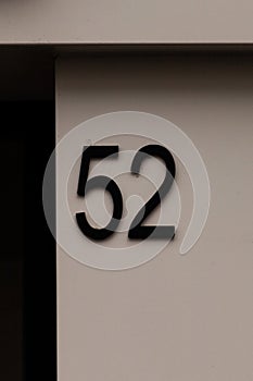 Number 52 black metal house number on white wall