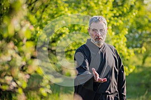 European sensei in black kimono practices tai chi in a sakura garden