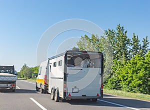 European-style horse box with horses pulled by minibus on hungarian road. Horse trailer on highway