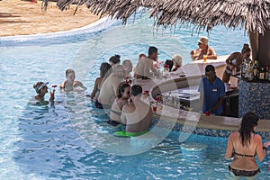 European tourists relaxing at the beach bar in the swimming pool at a tropical resort near the sea on the island of Zanzibar,