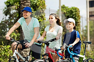 European tourists with son riding bicycles in park