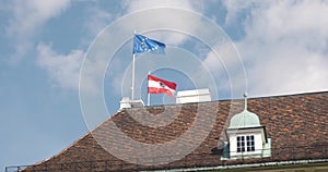 European Union and Austria flags on roof, waving in the wind in real time.