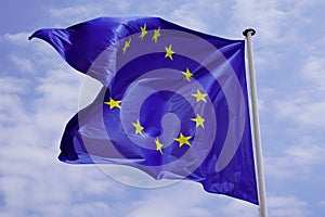 European Union EU Flag yellow stars Waving in mat on cloud blue sky background