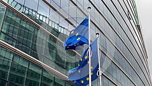 European Union flags flutter in wind against glass building facade background, Brussels, Belgium, Europe, August 5, 2023