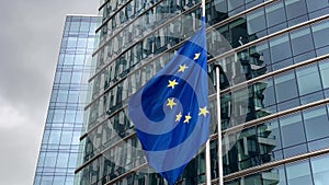 European Union flags flutter in wind against glass building facade background, Brussels, Belgium, Europe, August 5, 2023
