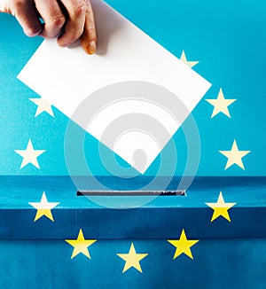 european Union parliament election concept - hand putting ballot in blue election box - EU flag