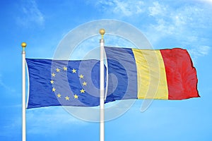 European Union and Romania two flags on flagpoles and blue cloudy sky