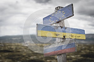 european union ukraine russia flag on wooden signpost outdoors in nature.