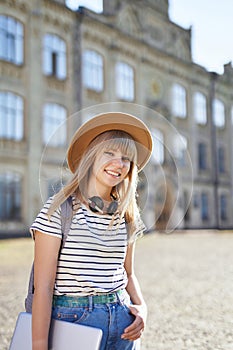 European university student girl in hat and laptop at campus