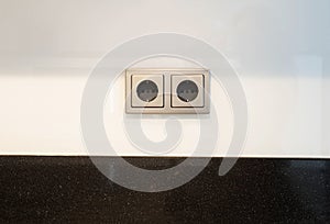 European white electrical outlet socket and black cable plugged in isolated on white wall