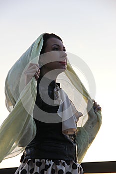 European woman in a black jacket, beige blouse and a shawl stole on her head looks away. portrait of a woman with red