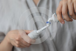 European woman brushing her teeth with an electric toothbrush, oral and dental care, human personal hygiene, toothpaste