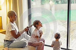 European woman combing and braiding hair of her child