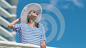 European woman having vacation enjoying sunlight on balcony of modern hotel