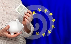 European woman with money bank on the background of EU flag. Dotations, pension fund, poverty, wealth, retirement concept