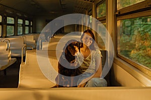 a European woman in sunglasses and a Labrador retriever dog in an empty train car are driving and looking out the window