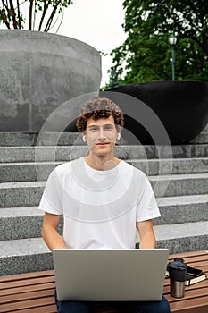 European young male in wireless earphones with laptop computer