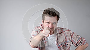 European young man menacingly stares into the camera and points his index finger, saying you are next. s photo